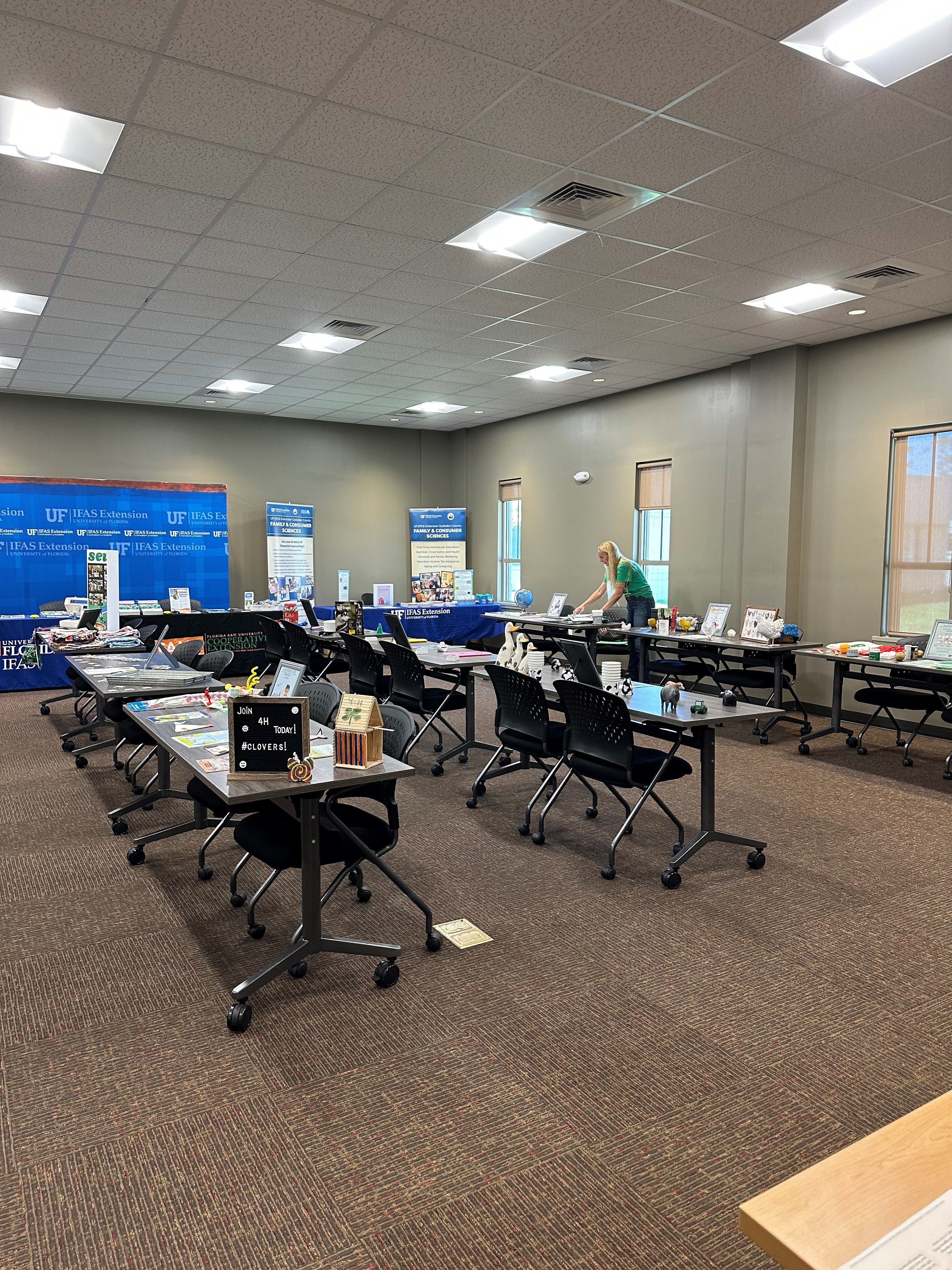 Indoor event space set up with rows of tables displaying informational materials and booths, hosted by the UF IFAS Extension.