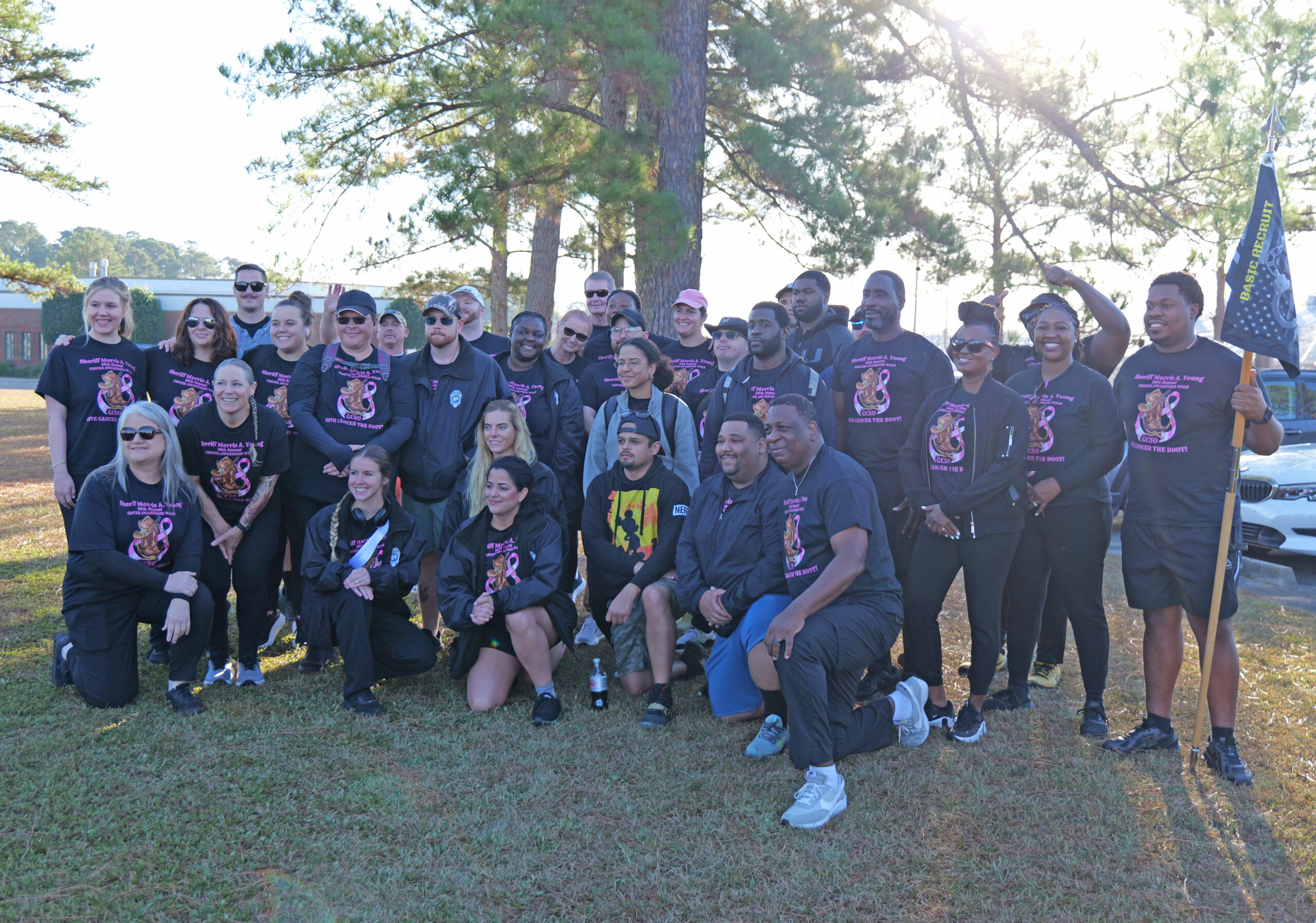 Group of people walking during a breast cancer awareness walk, with some wearing pink and others in themed shirts.