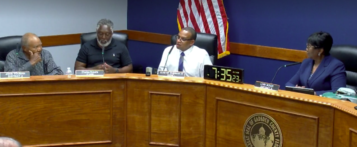 Gadsden County Board of County Commissioners meeting in session, with officials seated at the dais discussing agenda items in a formal chamber setting.